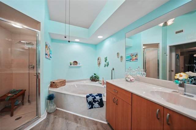 bathroom featuring a stall shower, visible vents, wood finished floors, a garden tub, and vanity