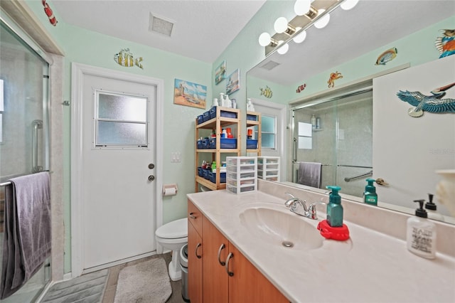 bathroom featuring a wealth of natural light, visible vents, toilet, a stall shower, and vanity