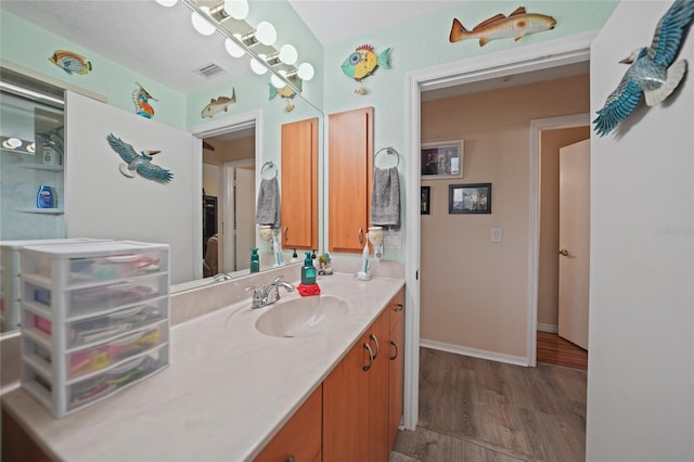 bathroom with baseboards, visible vents, wood finished floors, and vanity