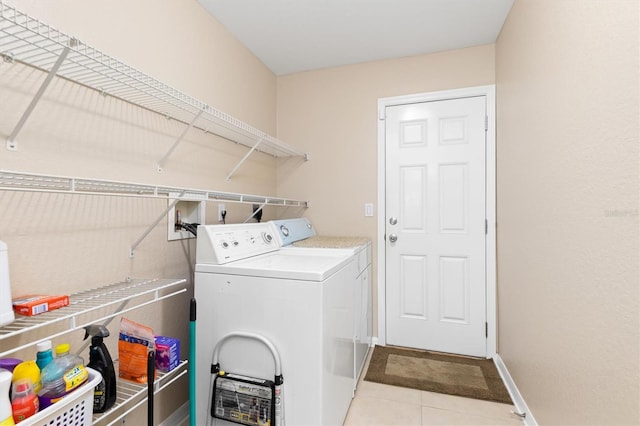 washroom with washer and dryer, laundry area, light tile patterned flooring, and baseboards