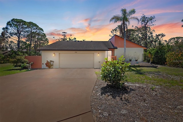 view of front of home featuring driveway, an attached garage, fence, and stucco siding