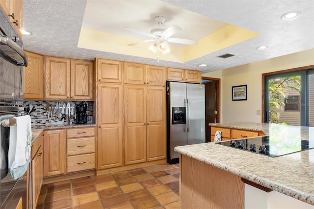 kitchen featuring black electric cooktop, visible vents, backsplash, stainless steel fridge with ice dispenser, and a tray ceiling