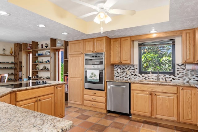 kitchen with tasteful backsplash, appliances with stainless steel finishes, a raised ceiling, and a sink