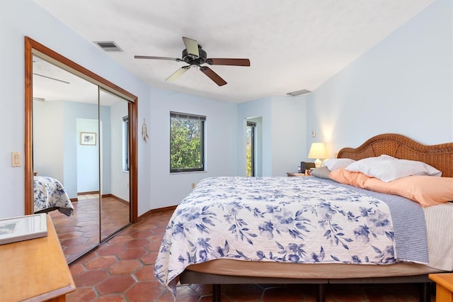 bedroom with ceiling fan, visible vents, baseboards, a closet, and tile patterned floors