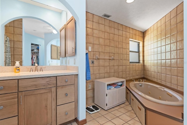 full bath with vanity, visible vents, tile walls, tile patterned floors, and a whirlpool tub