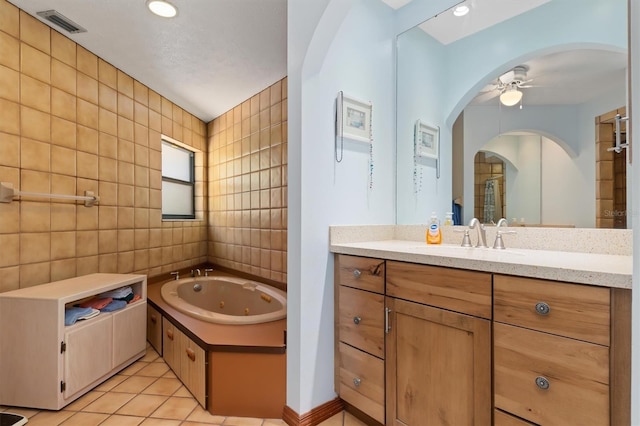 full bath featuring tile walls, visible vents, ceiling fan, a jetted tub, and tile patterned floors