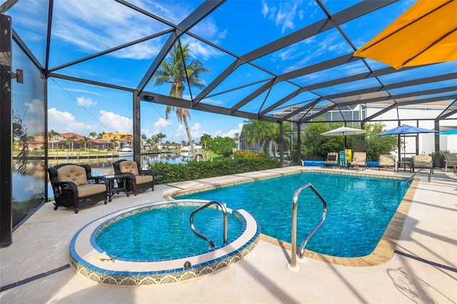 pool featuring glass enclosure, a patio area, and a water view