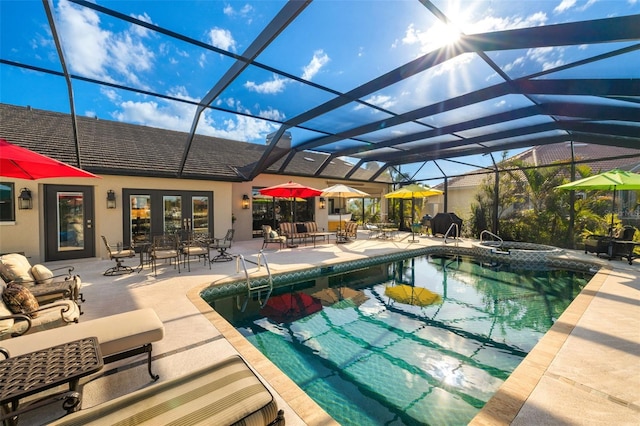 outdoor pool featuring glass enclosure, an in ground hot tub, a patio area, and french doors