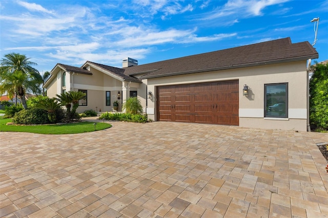 view of front of house with decorative driveway, an attached garage, and stucco siding