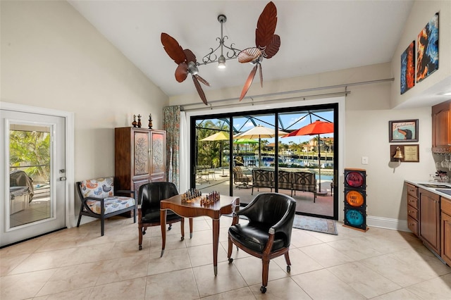 sitting room with ceiling fan, high vaulted ceiling, light tile patterned floors, a sunroom, and baseboards