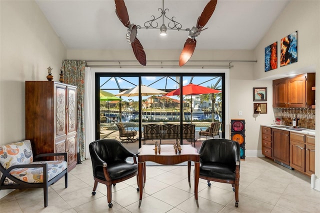 sitting room with light tile patterned floors, a sunroom, baseboards, vaulted ceiling, and wet bar