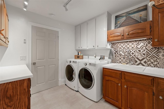 laundry area with independent washer and dryer, cabinet space, a sink, and track lighting