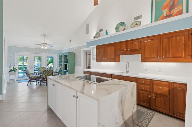 kitchen featuring visible vents, a kitchen island, black electric cooktop, french doors, and a sink