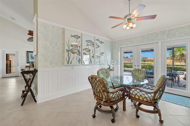 dining space with french doors, a wainscoted wall, light tile patterned floors, vaulted ceiling, and wallpapered walls