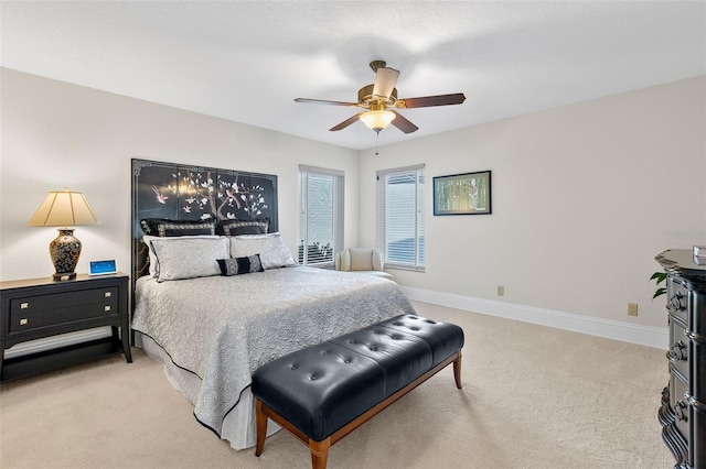 bedroom featuring light colored carpet, ceiling fan, and baseboards