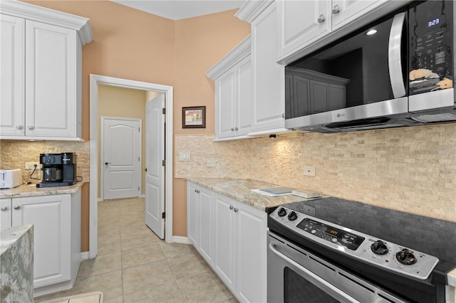 kitchen with stainless steel appliances, tasteful backsplash, white cabinetry, and light tile patterned floors