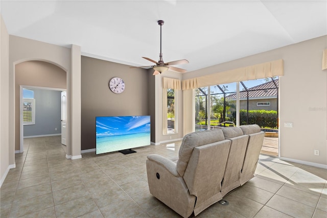 living area with a sunroom, ceiling fan, light tile patterned floors, and baseboards