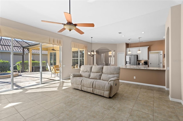 living room with light tile patterned floors, baseboards, arched walkways, and recessed lighting