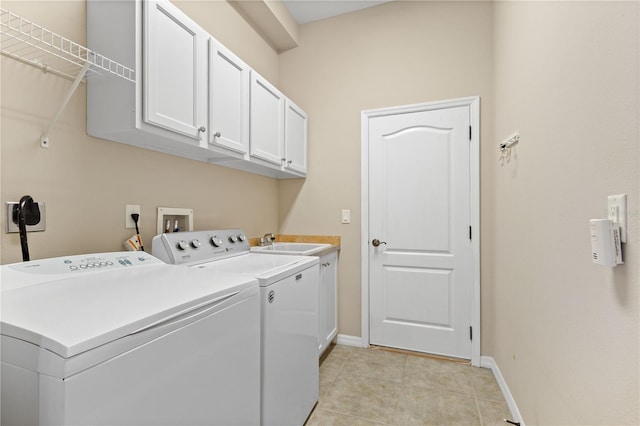 laundry area featuring cabinet space, light tile patterned floors, washer and clothes dryer, and a sink