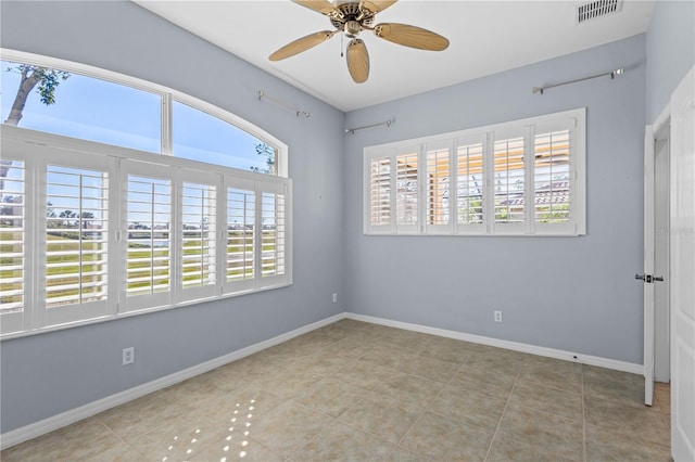 tiled empty room featuring ceiling fan, visible vents, and baseboards