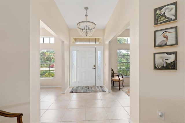 foyer with light tile patterned floors, baseboards, and a notable chandelier