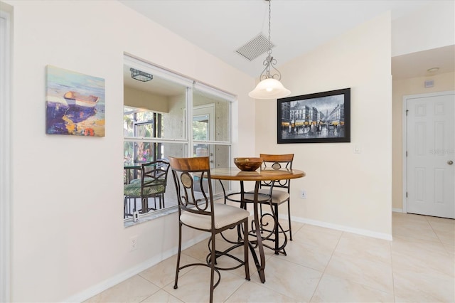 tiled dining area with lofted ceiling, visible vents, and baseboards