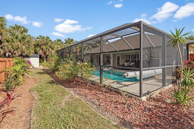 pool featuring an outbuilding, a lanai, a patio area, and fence