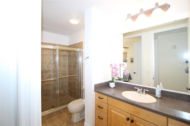 bathroom featuring vanity, a shower stall, toilet, and tile patterned floors