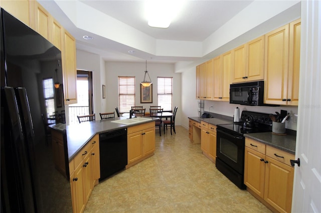 kitchen featuring light brown cabinets, a sink, black appliances, a tray ceiling, and dark countertops