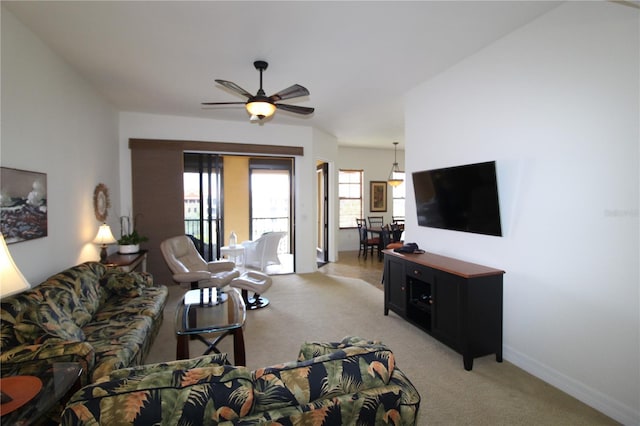 living room with light carpet, baseboards, and a ceiling fan