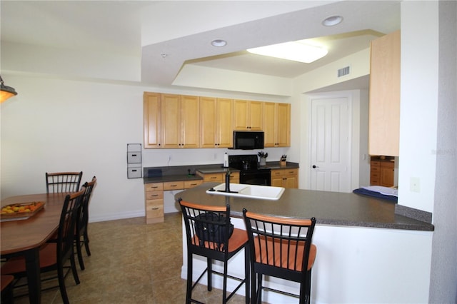 kitchen with black appliances, dark countertops, light brown cabinets, and visible vents