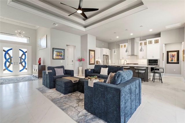 living room featuring a high ceiling, visible vents, marble finish floor, ornamental molding, and a tray ceiling