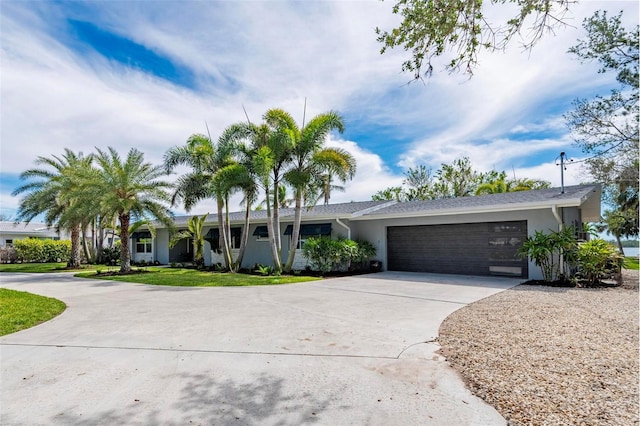 single story home with a garage, concrete driveway, a front lawn, and stucco siding