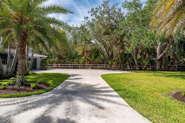 surrounding community featuring a garage, driveway, a lawn, and fence