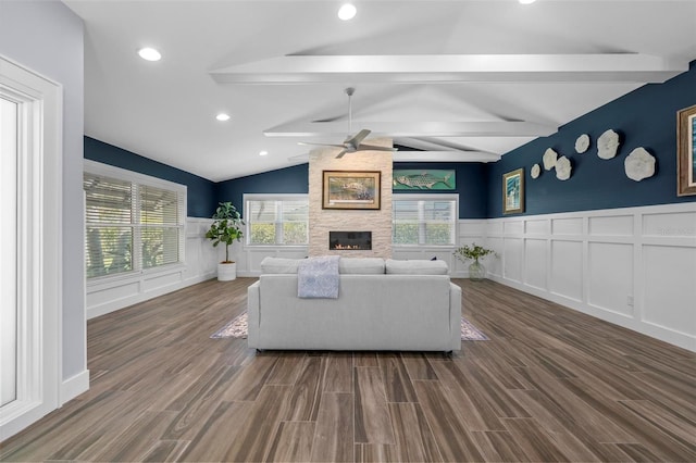 unfurnished living room featuring lofted ceiling with beams, a wainscoted wall, ceiling fan, wood finished floors, and a fireplace