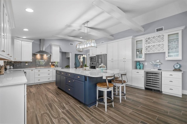 kitchen featuring wine cooler, blue cabinets, white cabinets, wall chimney range hood, and appliances with stainless steel finishes