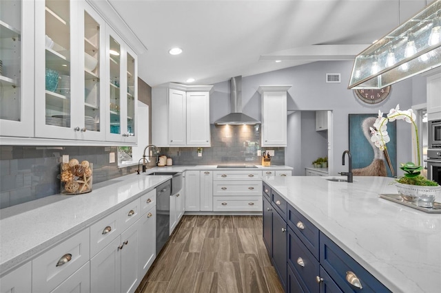 kitchen with white cabinetry, wall chimney exhaust hood, appliances with stainless steel finishes, and a sink