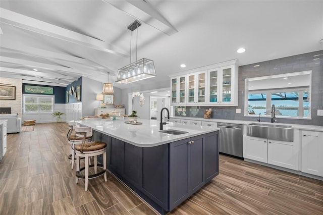 kitchen featuring open floor plan, white cabinetry, dishwasher, and a sink