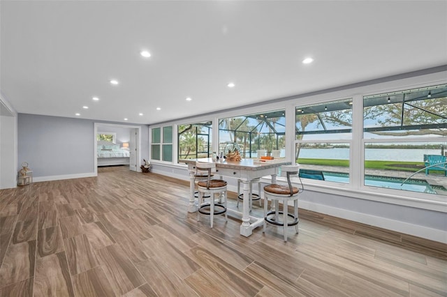 unfurnished dining area featuring a water view, wood finished floors, and recessed lighting