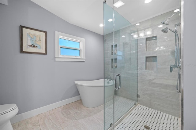 bathroom featuring a stall shower, toilet, a freestanding bath, and baseboards