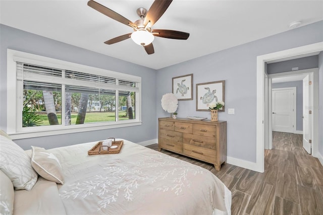 bedroom featuring a ceiling fan, baseboards, and wood finished floors