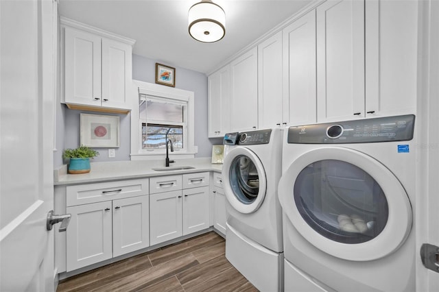 laundry room featuring wood finish floors, a sink, cabinet space, and washer and dryer