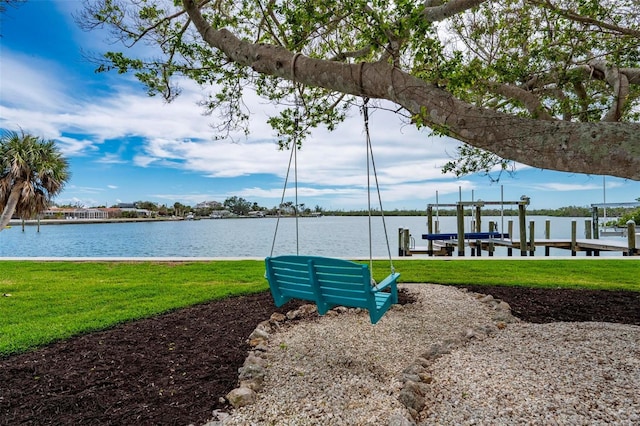 dock area featuring a water view, boat lift, and a yard