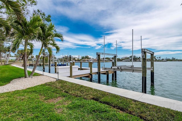 dock area featuring a water view, a lawn, and boat lift