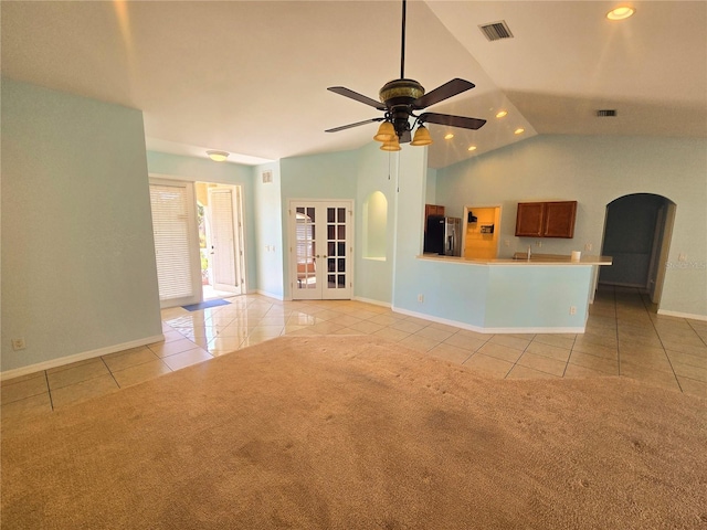 unfurnished living room featuring light carpet, light tile patterned floors, visible vents, and arched walkways