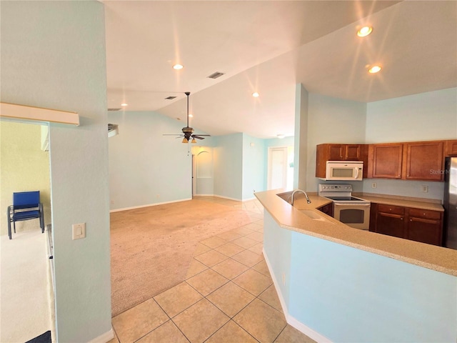 kitchen with white appliances, light colored carpet, lofted ceiling, light countertops, and a sink