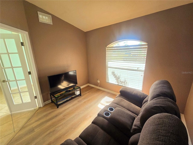 living area with vaulted ceiling, wood finished floors, visible vents, and baseboards