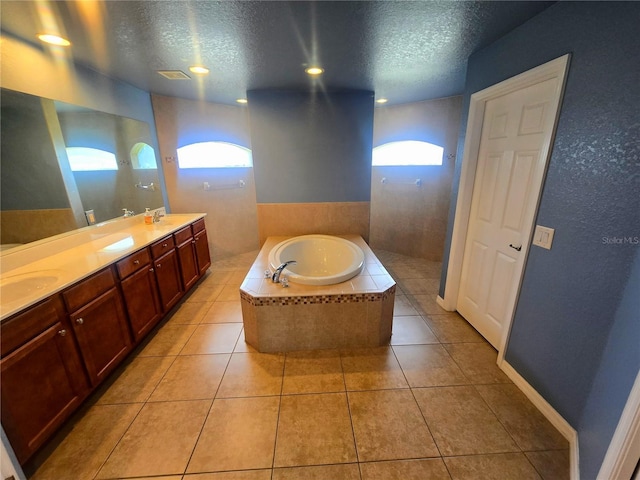 full bath featuring double vanity, tile patterned floors, a sink, a textured ceiling, and a bath