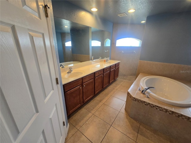 bathroom featuring double vanity, tile patterned floors, a sink, a textured ceiling, and a bath