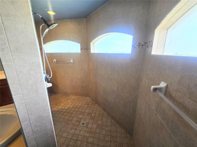 full bath featuring a tile shower and vanity